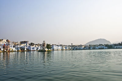 Scenic view of sea by buildings against clear sky