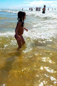 Children playing in sea on sunny day