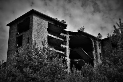 Low angle view of abandoned building by plants