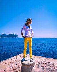 Man standing by sea against blue sky