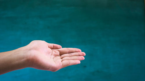 Close-up of hand against blue water