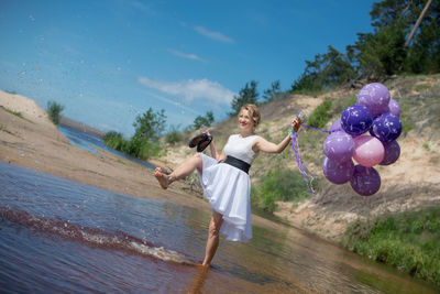 Woman kicking water and holding balloon