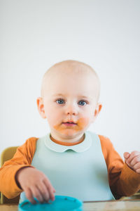 Portrait of baby girl with bib and messy mouth sitting at home