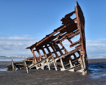 Old wooden structure on beach against sky