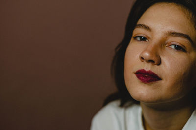 Close-up portrait of woman against brown background