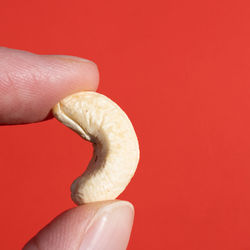 Close-up of hand holding cup against red background