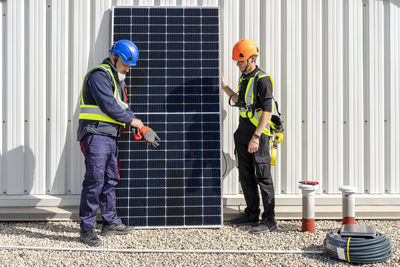 Colleagues standing by solar panel at power station