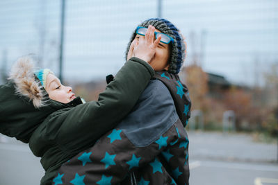 Side view of couple kissing woman during winter