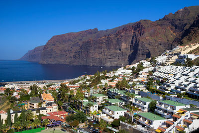 Buildings by sea against clear blue sky