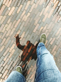 Low section of man walking on wet cobblestone street with reflection