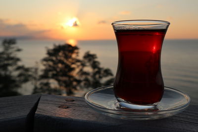 Close-up of tea in glass on table against sunset sky