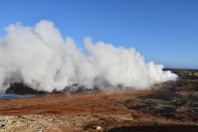 Smoke emitting from volcanic landscape against sky