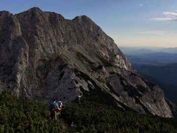 People on rocky mountains against sky