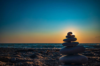 Stack of pebbles on beach during sunset