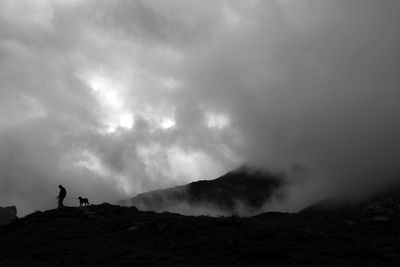 Low angle view of silhouette man standing on mountain against sky