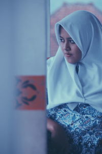 Close-up of young woman standing against wall