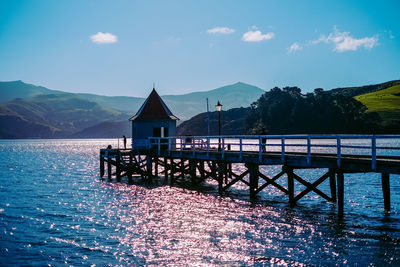 House by lake against sky
