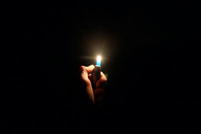 Close-up of hand holding lit candle