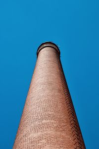 Low angle view of smoke stack against clear blue sky