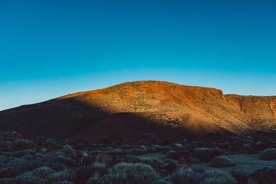 Scenic view of desert against clear blue sky