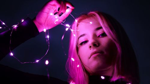 Portrait of woman with pink hair against black background