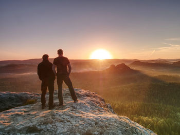 Hikers and friends stay on cliff within dreamy daybreak and thinking. dreamy foggy landscape