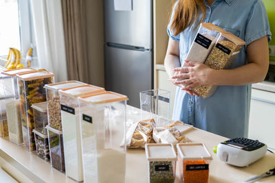 Midsection of woman holding grocery in container