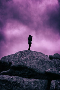 Rear view of silhouette woman standing on rock