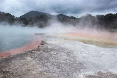 Steam emitting from geyser against sky