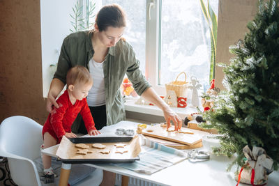 Happy mother and little baby toddler girl making christmas cookies in home kitchen. mother and