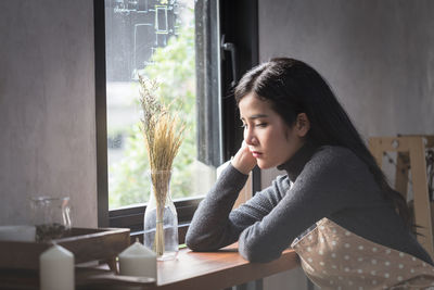 Thoughtful barista sitting at cafe