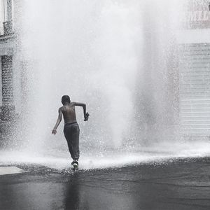 Full length of shirtless man splashing water