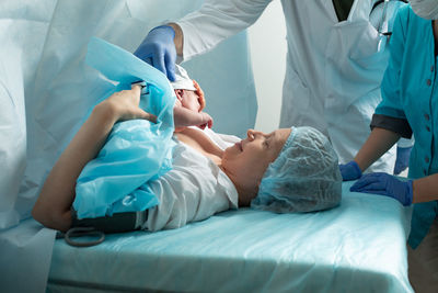 Midsection of doctor examining patient on bed