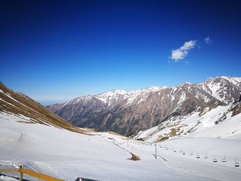 Scenic view of snowcapped mountains against blue sky