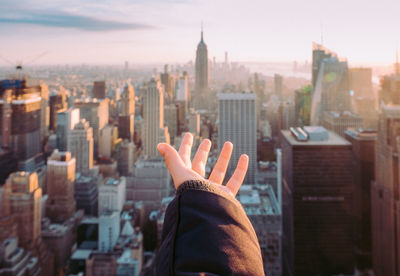 Midsection of person and buildings in city against sky