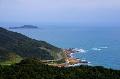 Scenic view of sea by mountains against clear sky