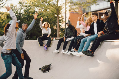 Friends dancing with hands raised in skateboard park