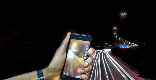 Close-up of hand photographing illuminated smart phone at night