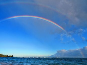 Scenic view of rainbow over sea against sky