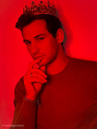 Portrait of young man standing against red background