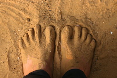 Low section of man standing on sand