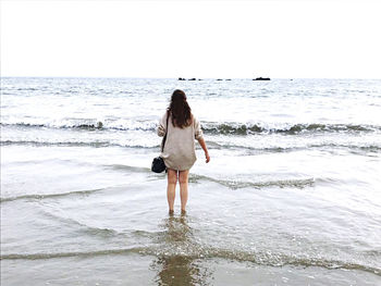 Rear view of woman standing on beach