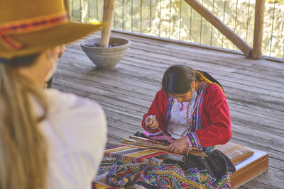 Indigenous woman showing traditional weaving technique and textile making in the andes mountain 