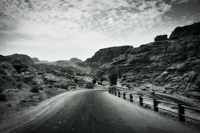 Road leading towards mountains against sky