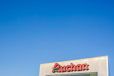 Low angle view of information sign against clear blue sky