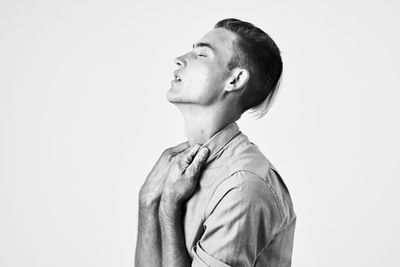 Portrait of young man looking away against white background