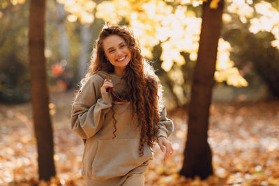 Portrait of young woman standing against trees