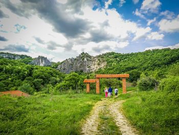 People on mountain against cloudy sky