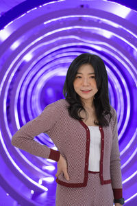 Portrait of young asian woman standing in futuristic purple circle of light