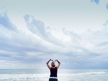 Rear view of person standing in sea against sky